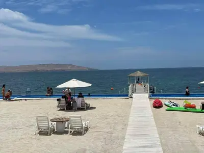 a beach with chairs and umbrellas next to the ocean at Condominio Nautico Paracas in Ica