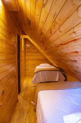 a room with two beds in a wooden cabin at Palo Alto Lodge in Oxapampa