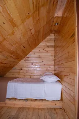 a bed in a wooden room with a wooden ceiling at Palo Alto Lodge in Oxapampa