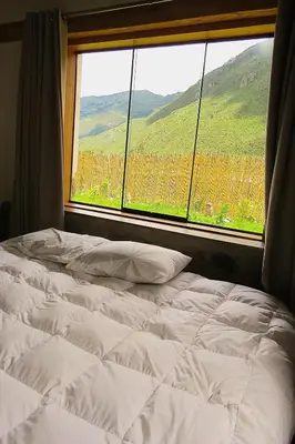 a bed in front of a window with a view at casa de campo con jaccuzi in Huaran