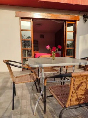 a table with two chairs and a vase with flowers at Casa Campo Isabel Quinteros in Chaclacayo