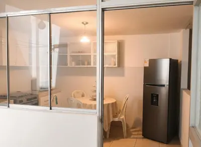 a kitchen with a black refrigerator and a table at Departamento Pisco - San Andrés, cerca a Paracas in Gallinazos Hacienda