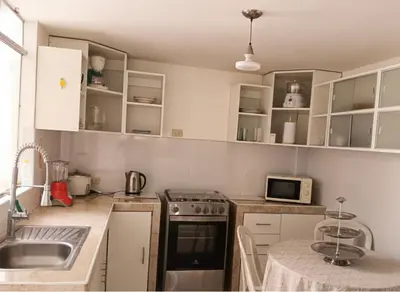 a kitchen with white cabinets and a stove top oven at Departamento Pisco - San Andrés, cerca a Paracas in Gallinazos Hacienda