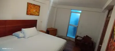 a bedroom with a white bed and a window at Suites Machupicchu in Machu Picchu