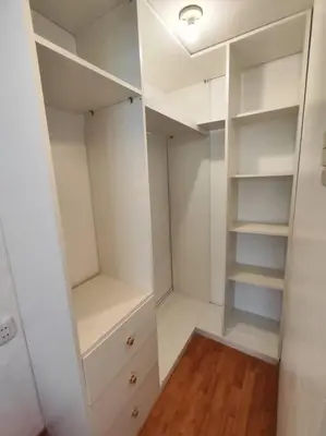 a white walk in closet with white cabinets and wood floors at Cómoda habitación independiente in Lima
