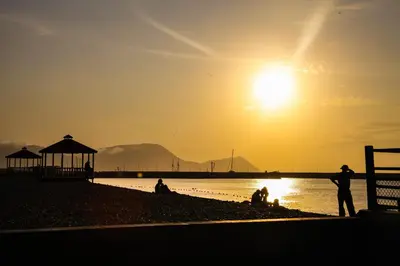 a group of people sitting on the beach at sunset at Villa La Punta in Lima