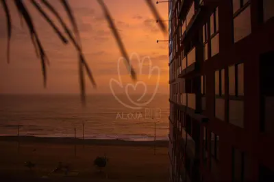 a sunset view of the ocean and a building at Departamento Vista al Mar Cerca Aeropuerto y Miraflores in Lima