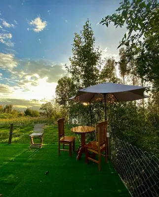a table and chairs with an umbrella and a bench at Antawara Glamping in Chipingura