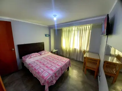 a bedroom with a bed and two chairs and a television at Hospedaje D Francisco in Lima