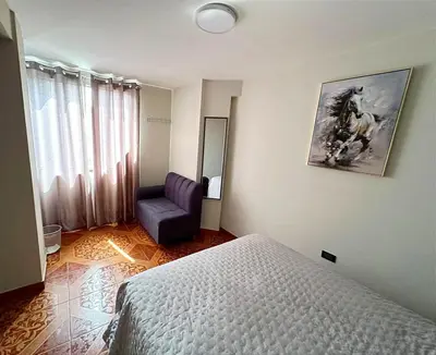 a bedroom with a bed and a purple chair at departamento airport in Lima