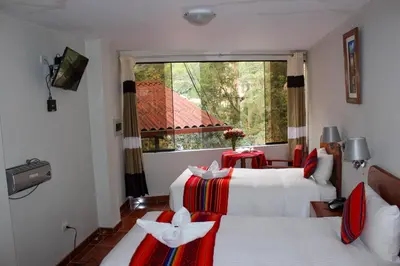 a hotel room with two beds and a window at Hotel Wiracocha Machupicchu in Machu Picchu