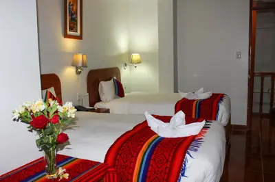 a hotel room with two beds and a vase of flowers at Hotel Wiracocha Machupicchu in Machu Picchu