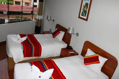 a hotel room with two beds and a window at Hotel Wiracocha Machupicchu in Machu Picchu