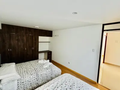 a bedroom with two beds and a mirror at Hermoso depa a 10 min del Centro de Huancayo in Huancayo