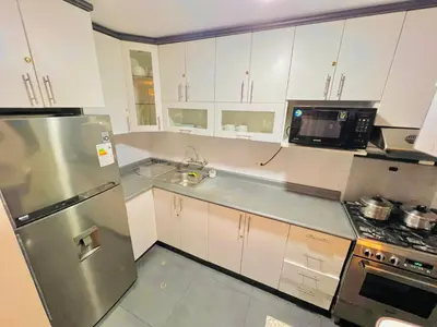 a kitchen with white cabinets and a stainless steel refrigerator at Apartamento en Santiago de Surco in Lima