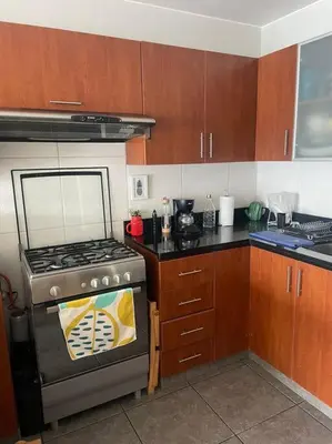 a kitchen with a stove and wooden cabinets at Departamento en Miraflores, Lima in Lima