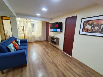 a living room with a blue couch and a tv at Departamento en La casa de Teresita in Cusco