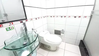 a bathroom with a toilet and a glass sink at Hotel Orlak in Huancayo