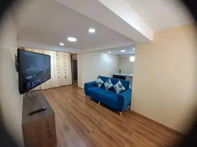 a living room with a blue couch and a flat screen tv at Departamento INTI - casa de Teresita in Cusco