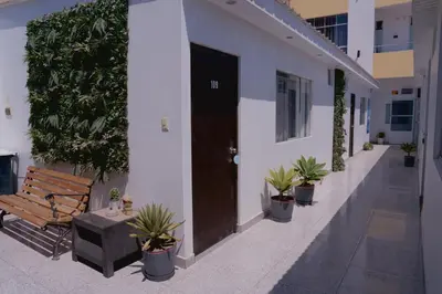 a wooden bench sitting next to a building with plants at Hotel San Martín in San Juan de Marcona
