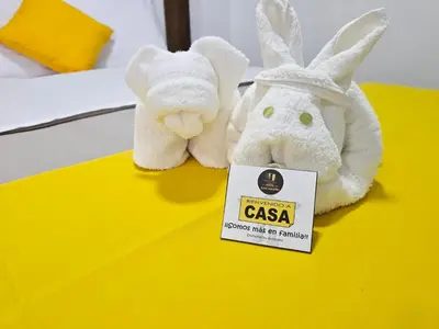 two stuffed animals sitting on a bed with a sign at Hotel San Martín in San Juan de Marcona