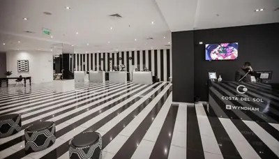a lobby with white chairs and a tv on a wall at Wyndham Costa del Sol Lima City in Lima