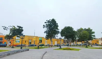 a park with benches and trees in front of a yellow building at Casa Turística Monumental in Lima