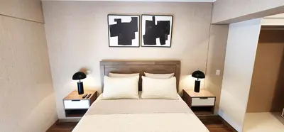 a bedroom with a bed with two tables and two pictures at Hermoso Departamento Miraflores in Lima