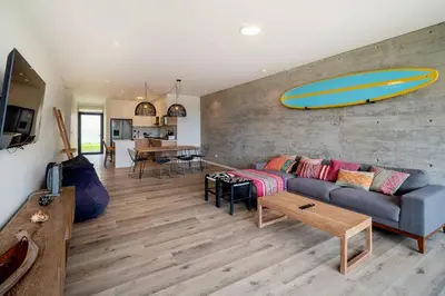 a living room with a couch and a surfboard on the wall at 2BR Spacious Ground Level with Gym Pool and Cowork in Paracas