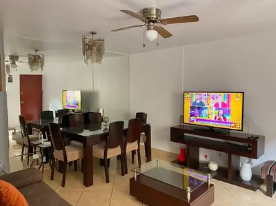 a living room with a dining table and a television at Cerca a las universidades San Marcos y Católica in Lima