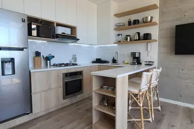 a kitchen with a counter and some chairs in it at Aldea 1BR Penthouse wtih Private Pool and Views for 2 in Paracas