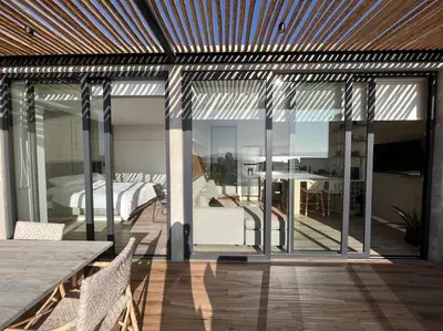 a room with sliding glass doors and a bedroom with a bed at Aldea 1BR Penthouse wtih Private Pool and Views for 2 in Paracas