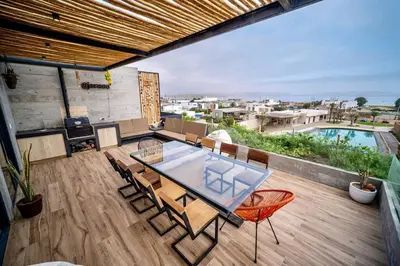 a patio with a glass table and chairs on a deck at Aldea 1BR Bohemian Rooftop Ocean View for 2 in Paracas