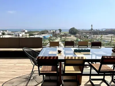 a table and chairs on a patio with a view at Aldea 1BR Bohemian Rooftop Ocean View for 2 in Paracas
