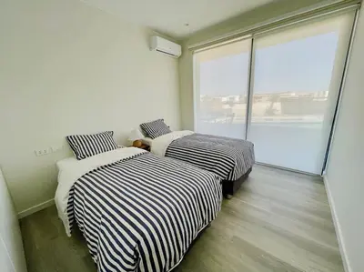 two beds in a room with a large window at Aldea 2BR Boho Style for 4 with Gym, Pool and Cowork in Paracas