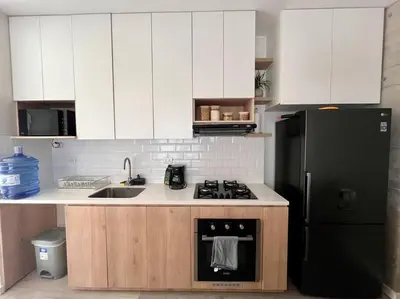 a kitchen with white cabinets and a black refrigerator at Aldea 2BR Family, Big FrontYard for 6 with Gym and Pool in Paracas