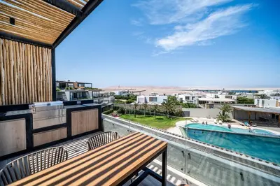 a balcony with a table and a swimming pool at Aldea 1BR Romance Seascape for 2 in Paracas