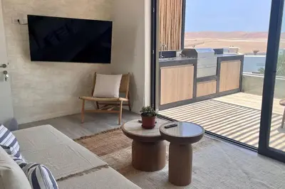 a living room with a flat screen tv and a balcony at Aldea 1BR Romance Seascape for 2 in Paracas