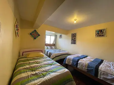 a bedroom with three beds in a room at Departamentos Belén in Cusco
