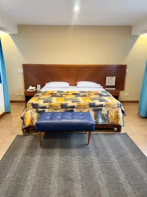 a bedroom with a bed with a wooden head board at Hotel Esencia Suites in Lima