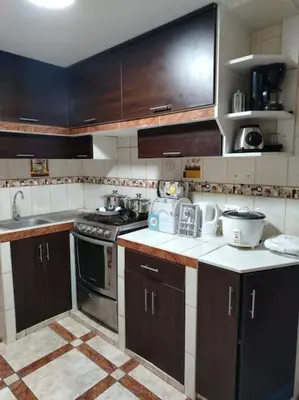 a kitchen with brown cabinets and a stove top oven at Apartamento acogedor en La Perla in Lima
