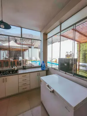 a kitchen with large windows and a view of a pool at CASA RICARDO PALMA con PISCINA in Ricardo Palma