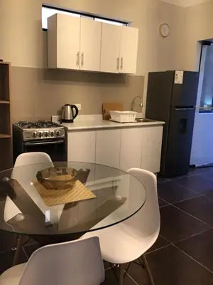 a kitchen with a glass table and white cabinets at Hernandez suites Suite203 in Lima