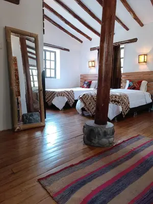 a room with three beds and a rug on the floor at Tika bungalows hotel in Ollantaytambo