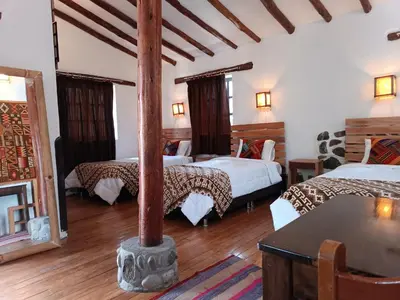 a room with three beds and a pole in it at Tika bungalows hotel in Ollantaytambo