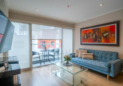 a living room with a blue couch and a glass table at Luxury Flat Miraflores Pool Gym Fast WiFi Balcony in Lima