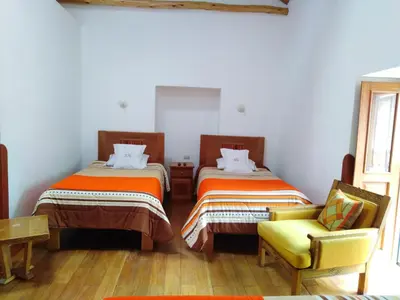 a room with two beds and a chair in it at Casa San Pedro Cusco in Cusco