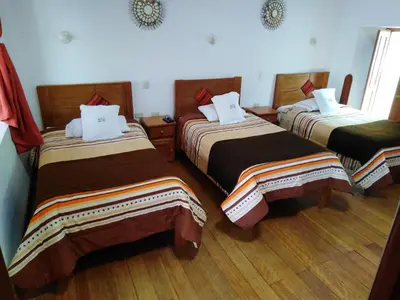 a hotel room with three beds in a room at Casa San Pedro Cusco in Cusco