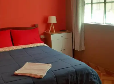 a red bedroom with a blue bed with a red pillow at Hermanas Pimentel in Ica