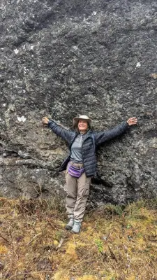 a woman standing on a rock with her arms out at EcoLodge Mayu Camping in Cusco
